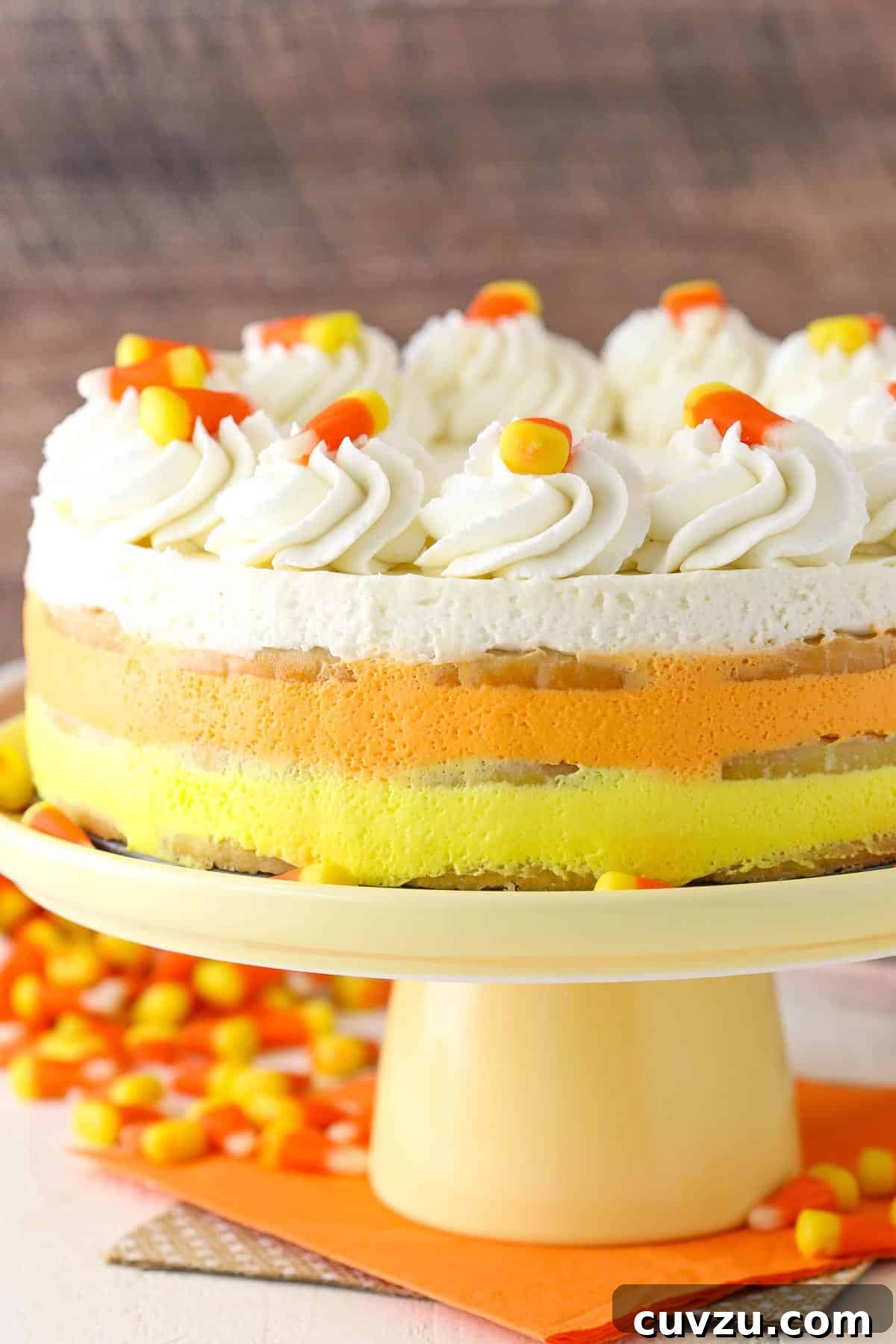 No-Bake Candy Corn Dream 3 A vibrant Candy Corn Icebox Cake presented on an elegant yellow cake plate, showcasing its beautiful layered structure.