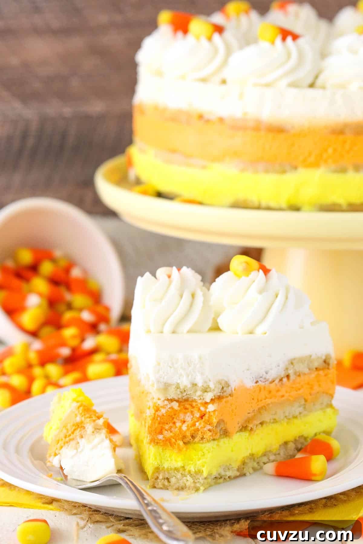 No-Bake Candy Corn Dream 6 A slice of Candy Corn Icebox Cake on a small white plate, showing a bite removed, emphasizing its soft and creamy texture.