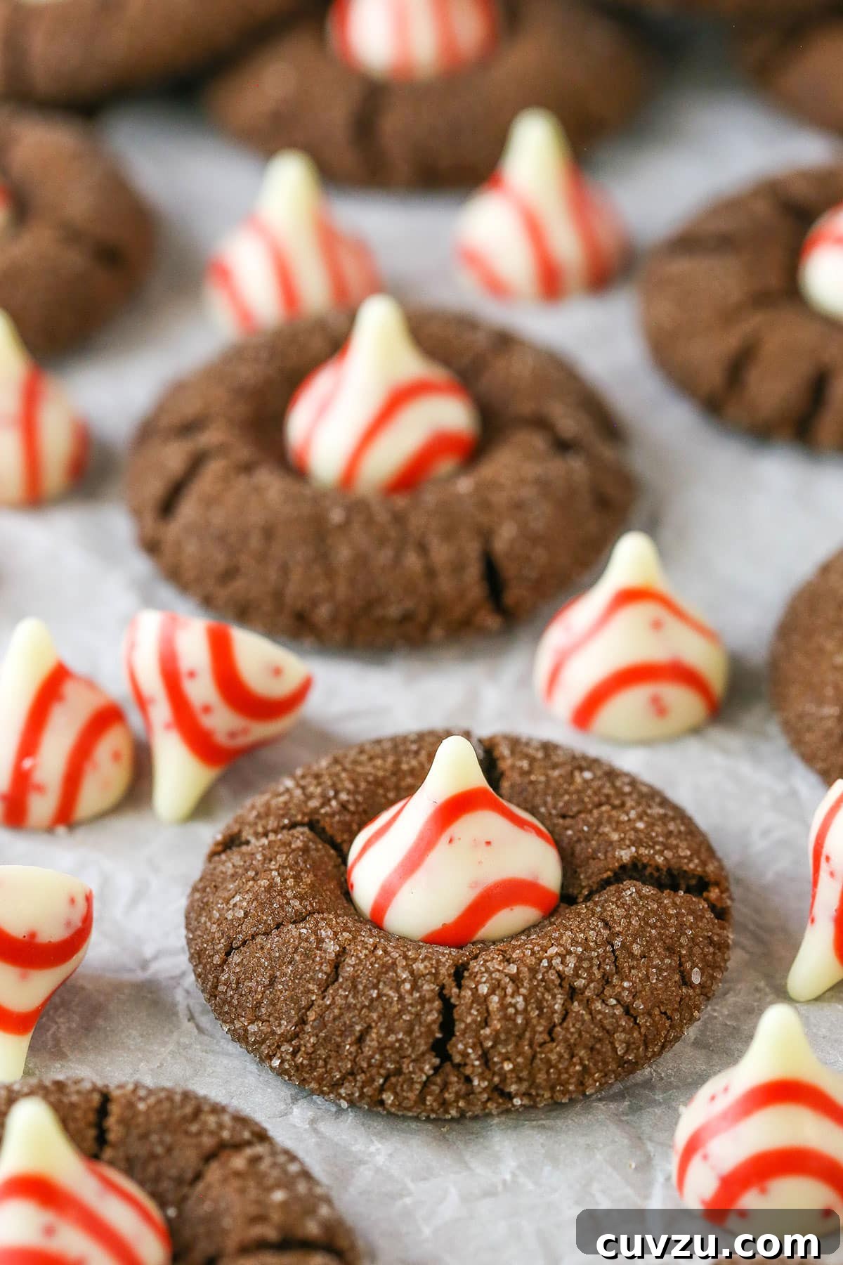 Perfectly baked Peppermint Chocolate Thumbprint Cookies with melting Hershey Kisses. A close-up of a batch of Peppermint Chocolate Thumbprint Cookies cooling on a rack, showcasing the perfect placement of the Hershey Kisses.