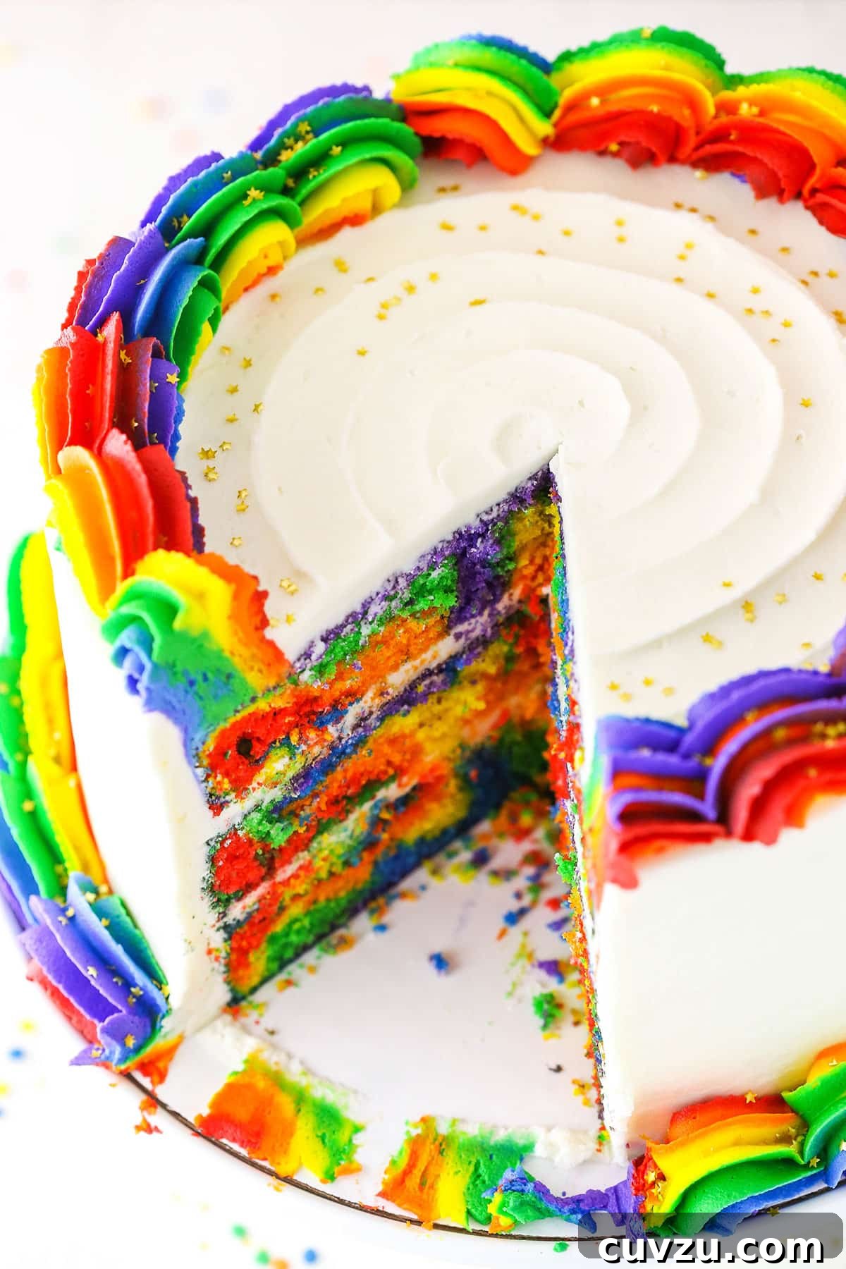 Kaleidoscope Cake 4 A Rainbow Swirl Cake with a single slice removed, showcasing the vibrant and distinct internal layers of rainbow-colored cake.