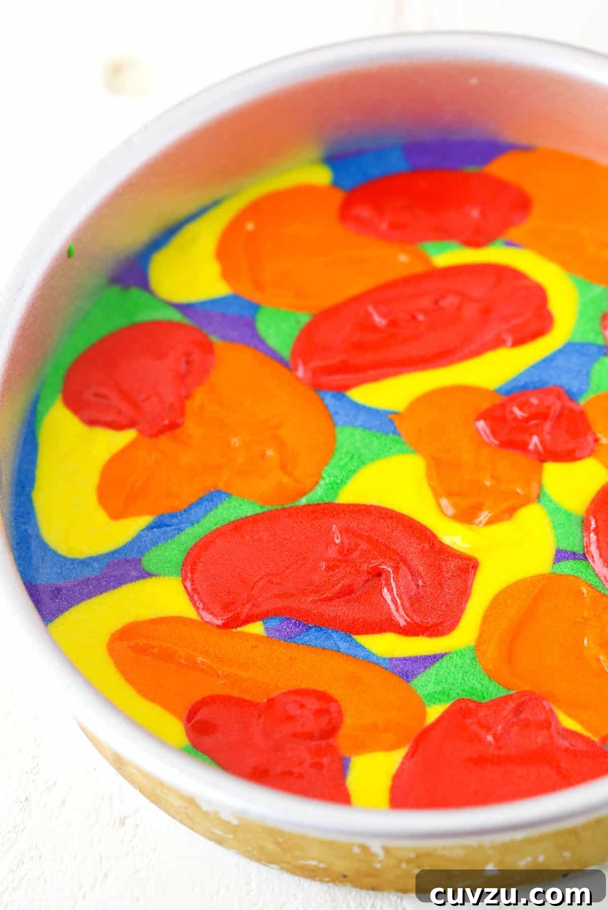 Kaleidoscope Cake 7 Another step in creating the Rainbow Swirl Cake, showing the technique of gently spreading layered colored batters to enhance the swirl pattern.