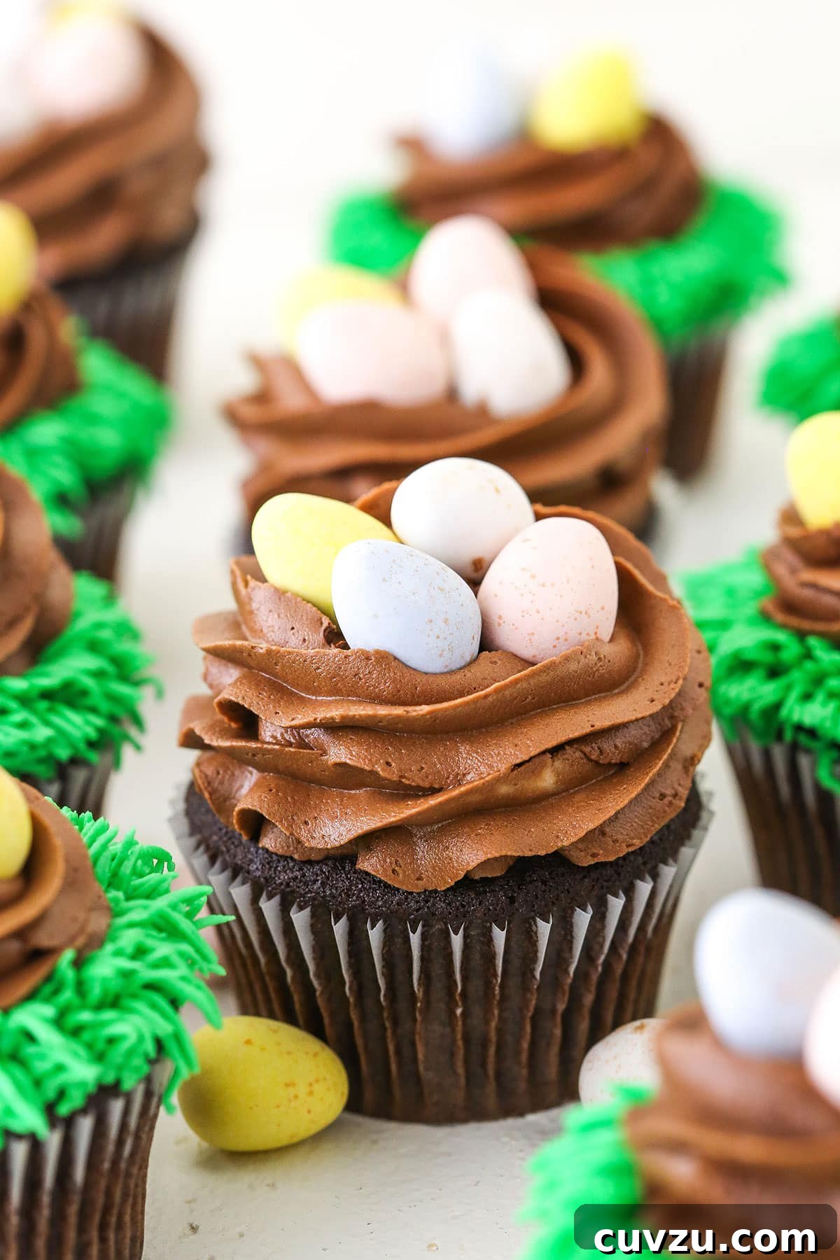 Easter Egg Chocolate Cupcakes on White Surface Artfully arranged Easter Egg Chocolate Cupcakes on a pristine white table, showcasing their elegant decorations.