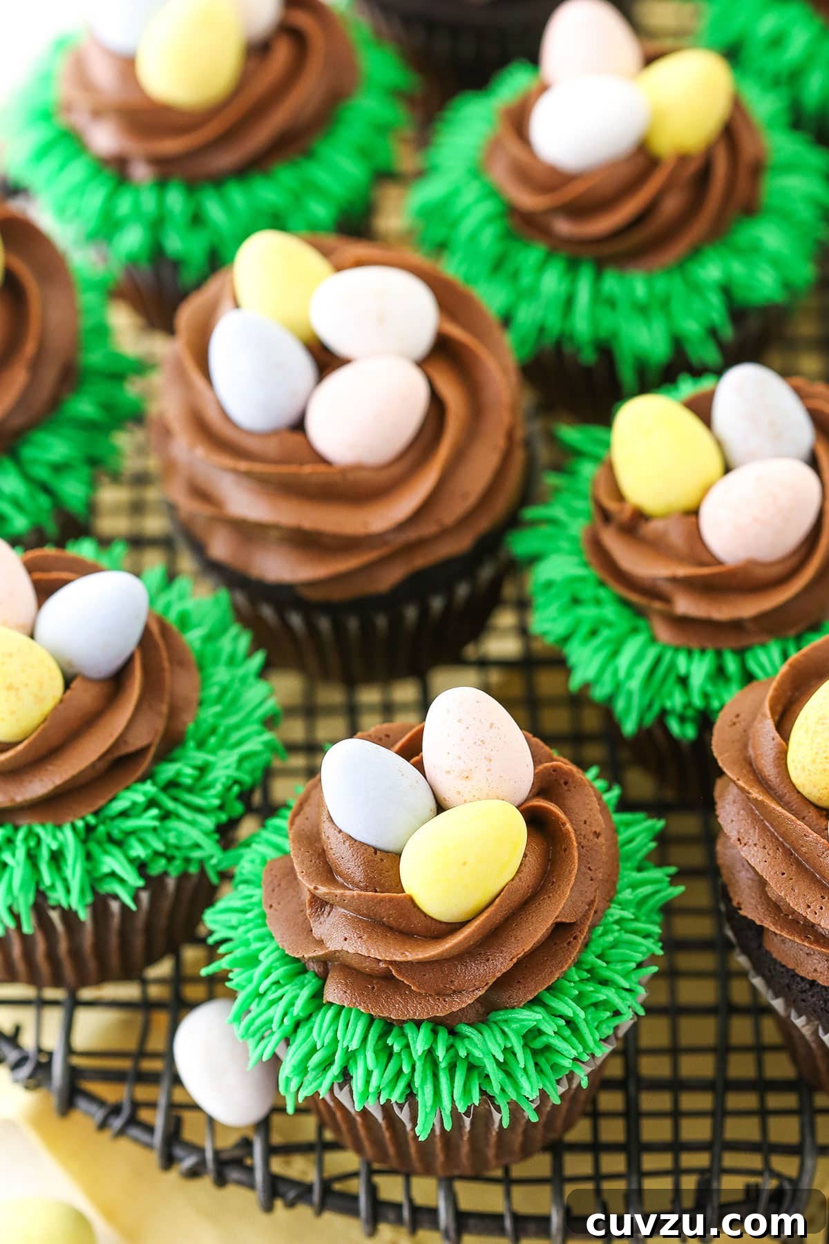 Overhead View of Easter Egg Chocolate Cupcakes An inviting overhead view of Easter Egg Chocolate Cupcakes, thoughtfully arranged on a gray wire cupcake stand, highlighting their delightful nest designs.