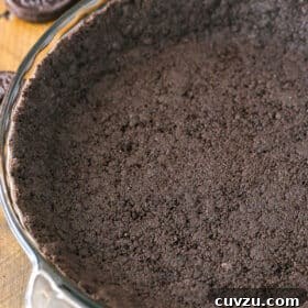 Oreo Cookie Crust in a clear glass pan on a wooden table