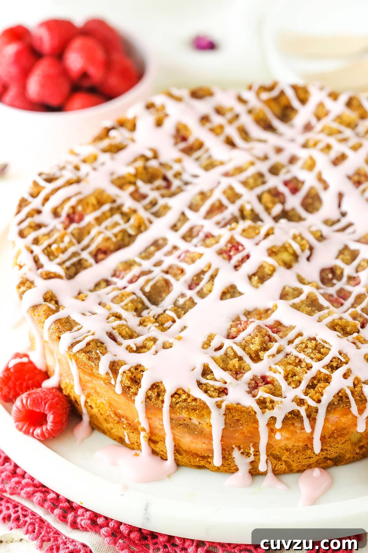 Raspberry Rose Coffee Cake: A delightful breakfast treat with vanilla rose cream cheese filling, fresh raspberries, cinnamon streusel, and rose glaze. A beautifully baked Raspberry Rose Coffee Cake on a white serving platter, garnished with fresh raspberries, ready to be enjoyed as a gourmet breakfast or brunch item.