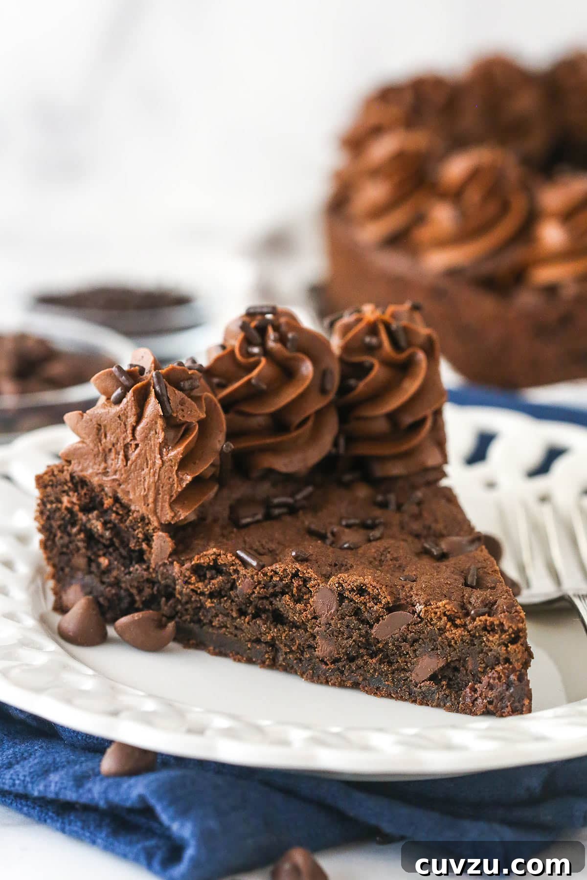 A perfect slice of Triple Chocolate Cookie Cake, ready to be enjoyed. A glorious slice of triple chocolate cookie cake, showcasing its rich layers and fudgy texture, served on a pristine white plate.