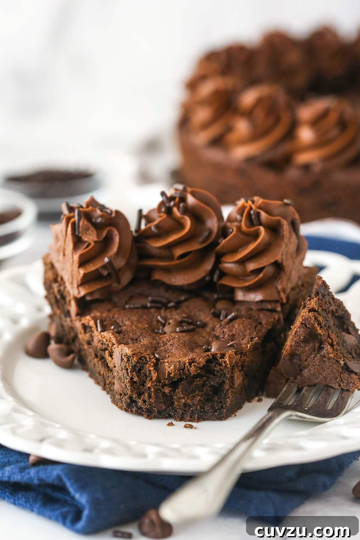 Enjoying a bite of the rich Triple Chocolate Cookie Cake. A fork piercing a delectable slice of triple chocolate cookie cake, ready for a bite, highlighting its soft texture.