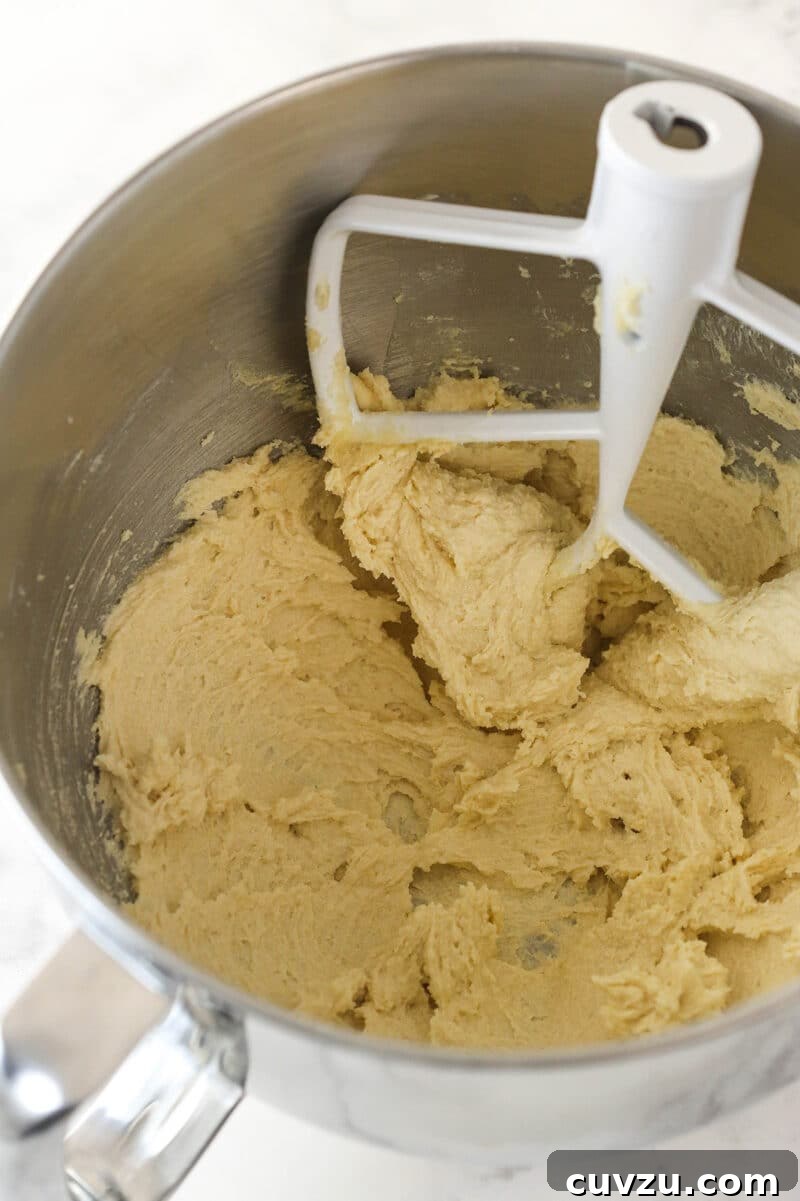 Cream butter and sugar until light and fluffy. The process of creaming together softened butter and sugars in a mixing bowl for the cookie cake batter.
