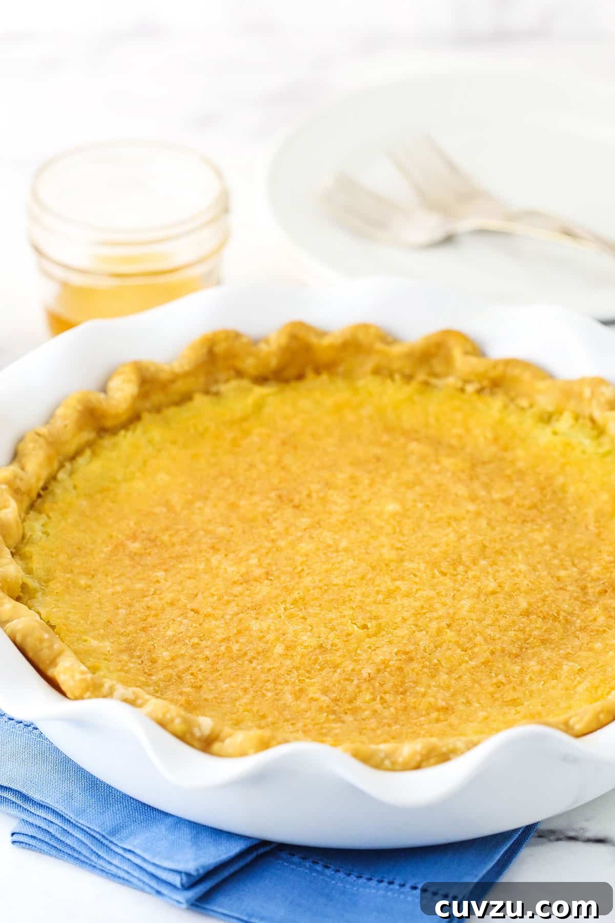 A stunning side profile of the perfectly baked Vinegar Pie. Side view of a complete Vinegar Pie in a white platter, resting on a blue placemat.