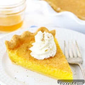 A slice of Vinegar Pie with a whipped cream swirl on a white plate next to a fork