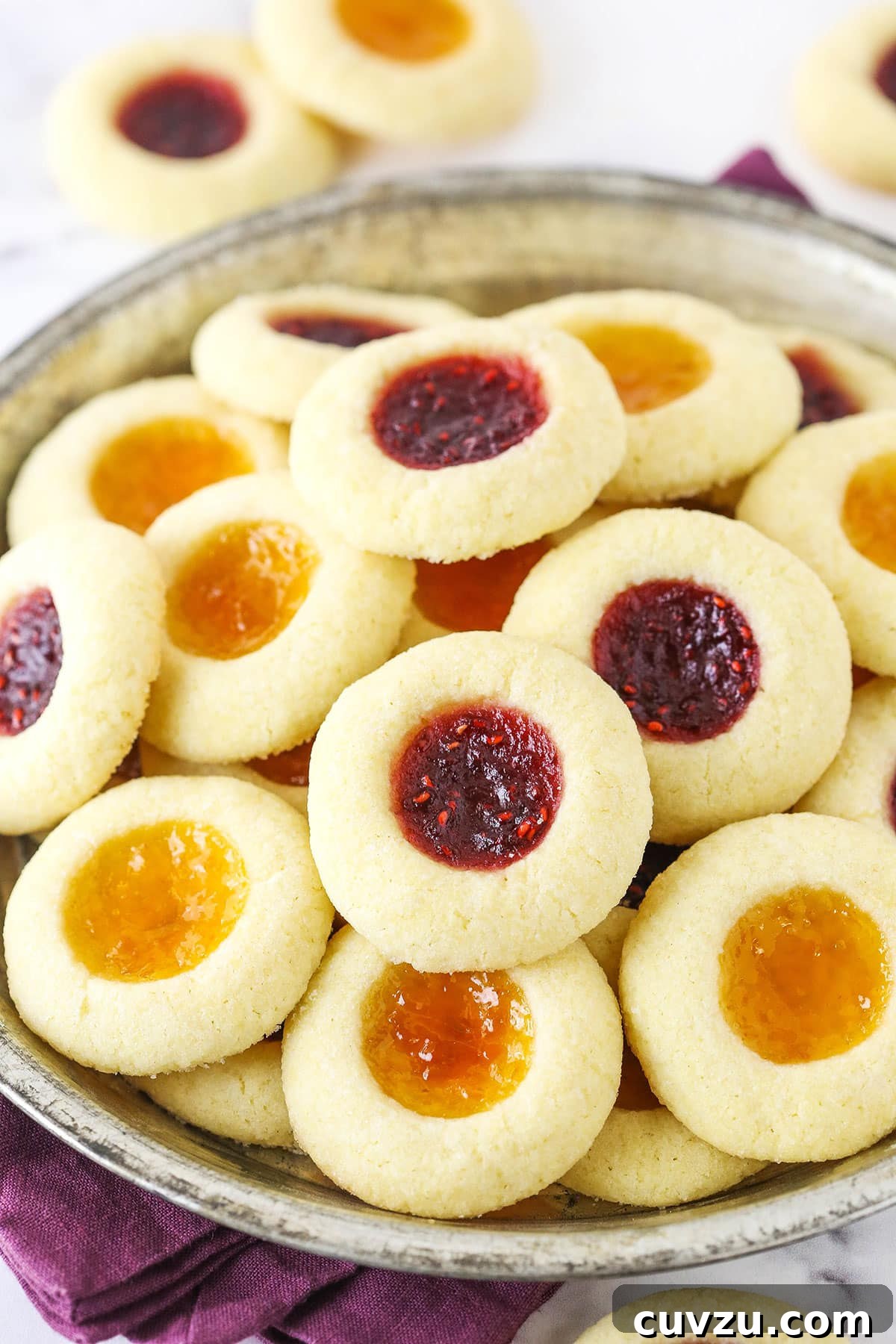 These classic thumbprint cookies are soft and chewy, filled with your favorite jam or preserves. Perfect for Christmas and easy to make! Jam thumbprint cookies piled on a silver platter.