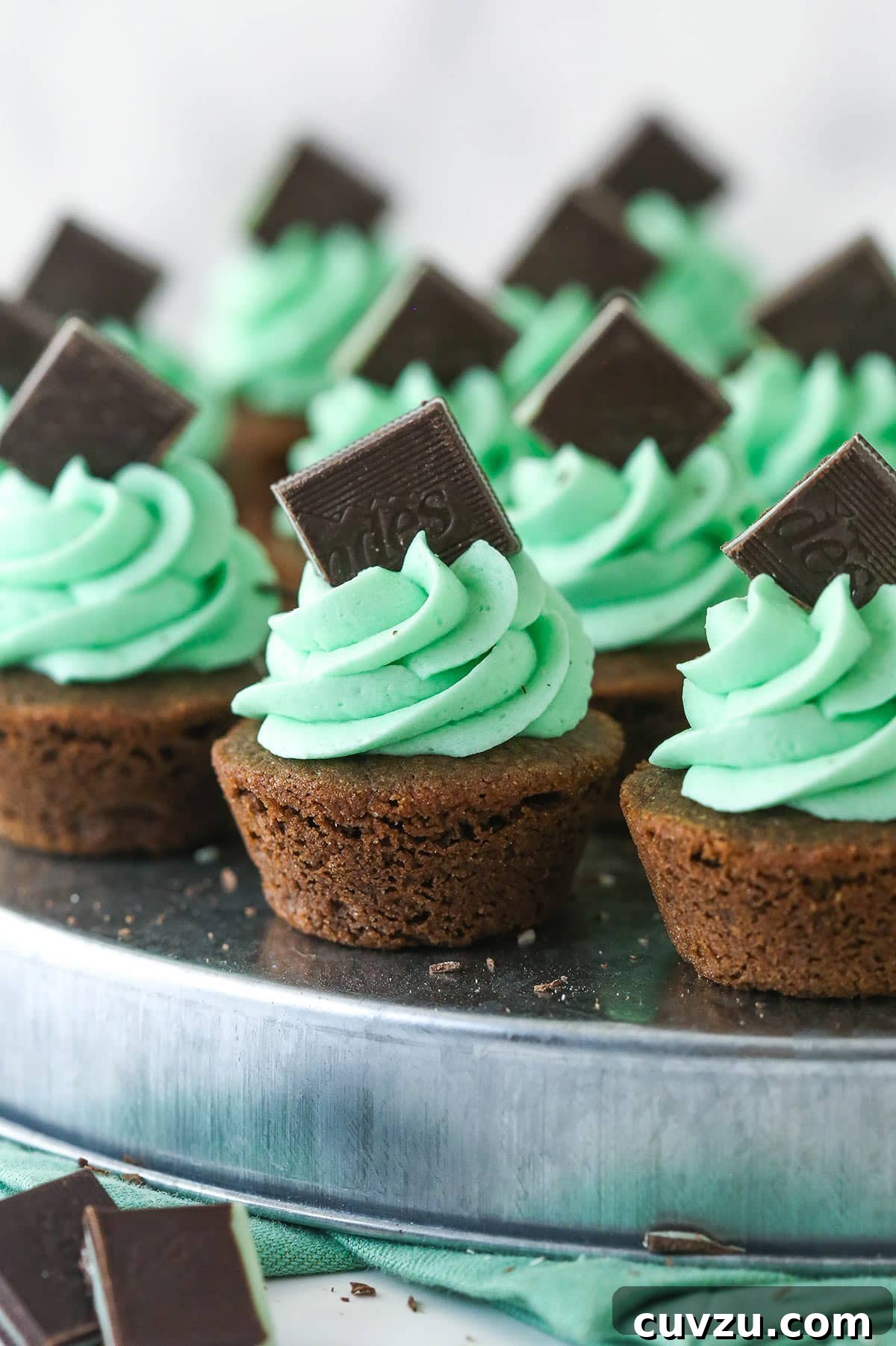 Decadent Mint Chocolate Cookie Cups 2 A close-up shot of Mint Chocolate Cookie Cups, showing the soft chocolate cookie, melted Andes Mint center, and green mint buttercream frosting.