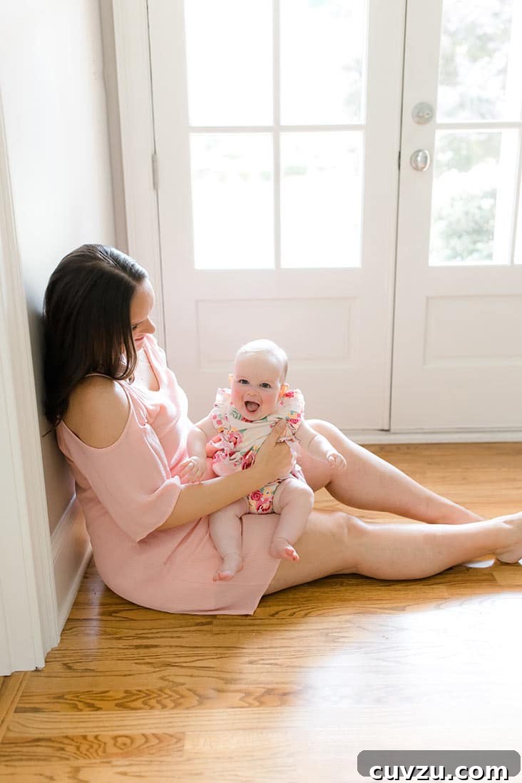 McKenzie's Seven-Month Adventure 2 Lindsay sitting by doorway with McKenzie smiling on lap, celebrating 7 months