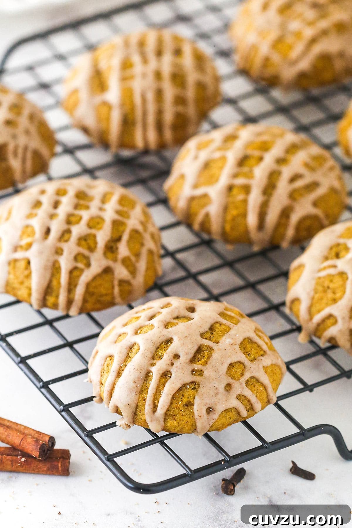 Pillowy Pumpkin Delights 10 Overhead view of pumpkin cookies with cinnamon glaze drying on a cooling rack.