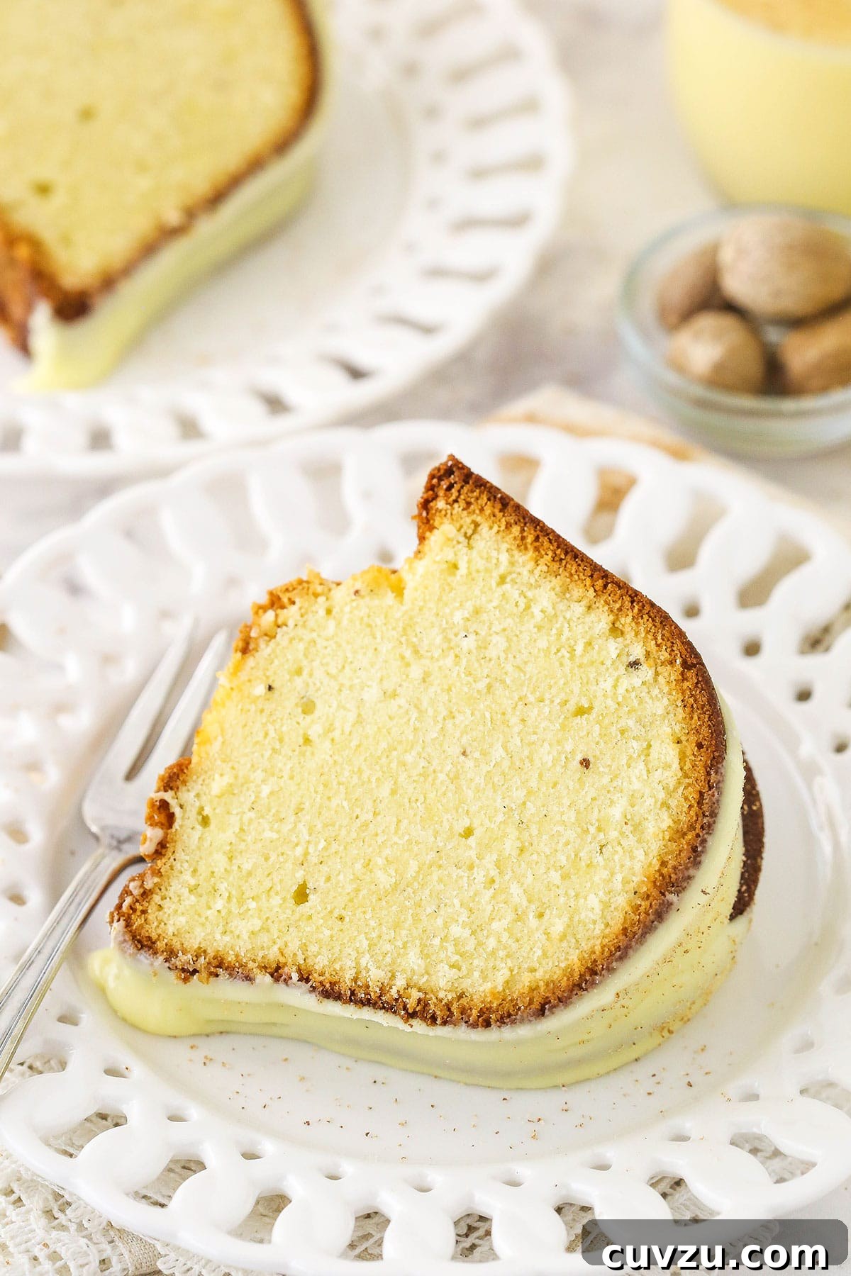 Velvet Eggnog Pound Cake 4 A slice of eggnog pound cake with a generous drizzle of eggnog glaze, presented on a decorative plate with festive cut-outs on the rim.