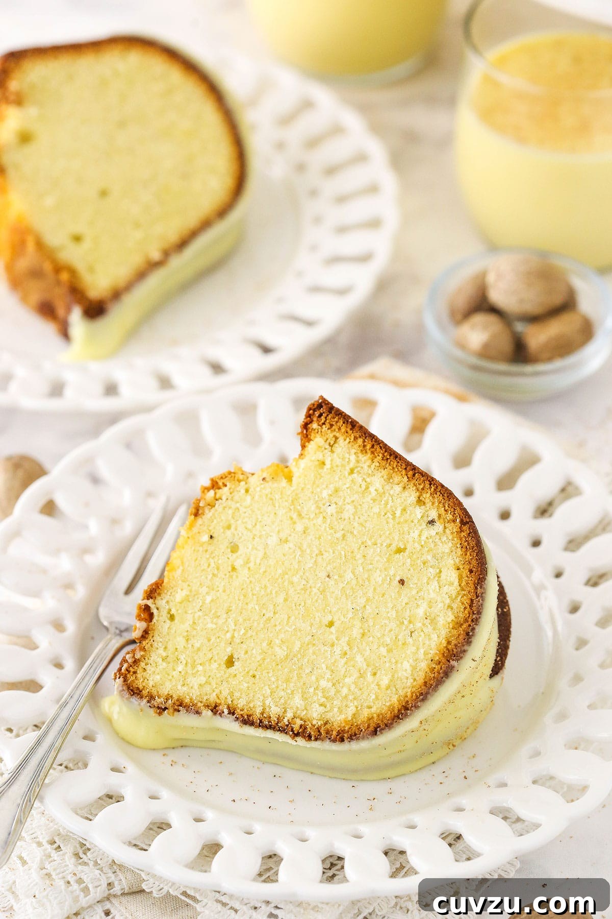 Velvet Eggnog Pound Cake 6 Two slices of iced eggnog bundt cake on plates, ready to be served, showcasing the rich texture and festive glaze.