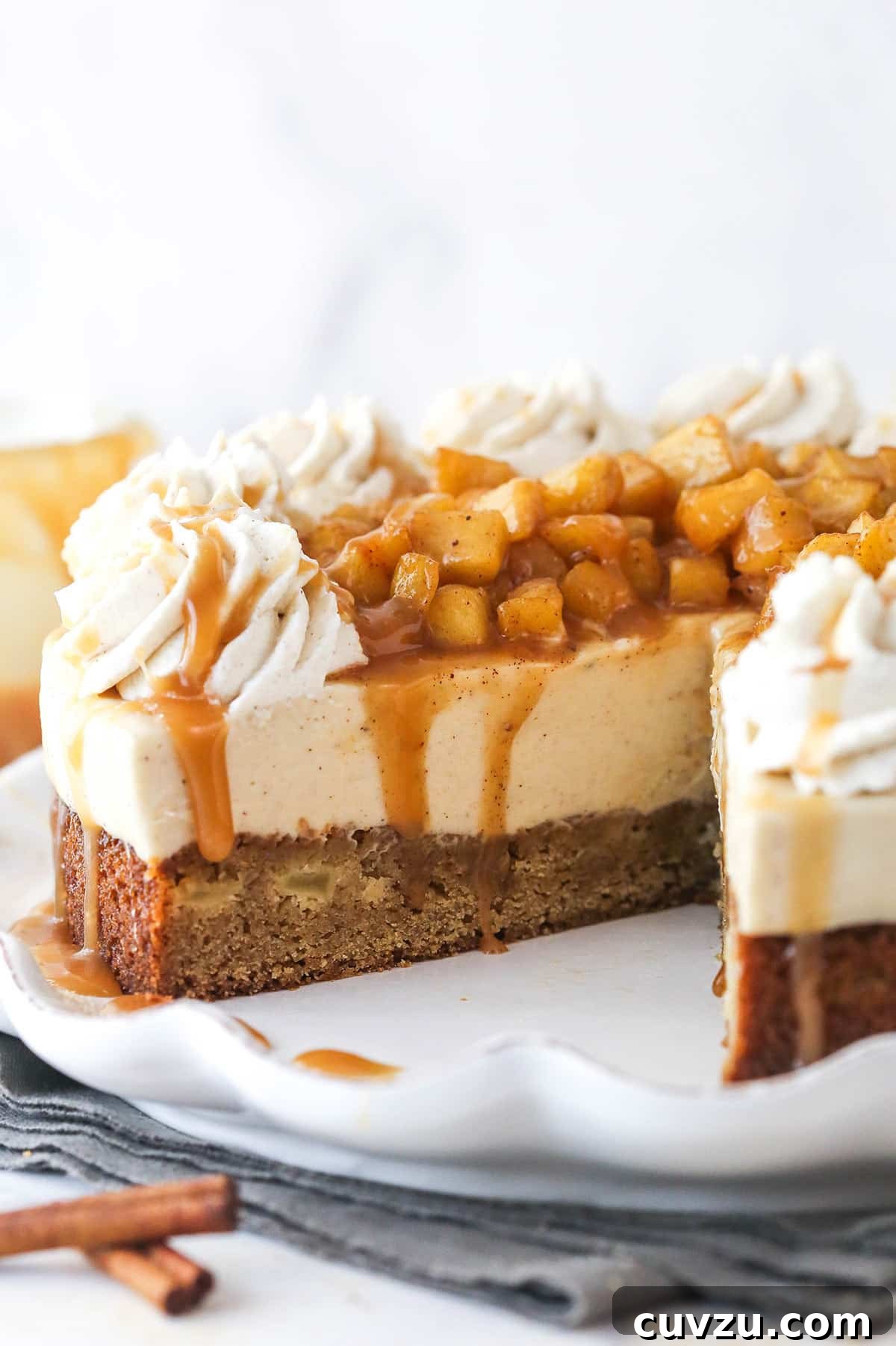 Decadent Caramel Apple Blondie Cheesecake 2 A Caramel Apple Blondie Cheesecake with a slice removed to show inner layers, showcasing the blondie base, creamy cheesecake, and apple topping.