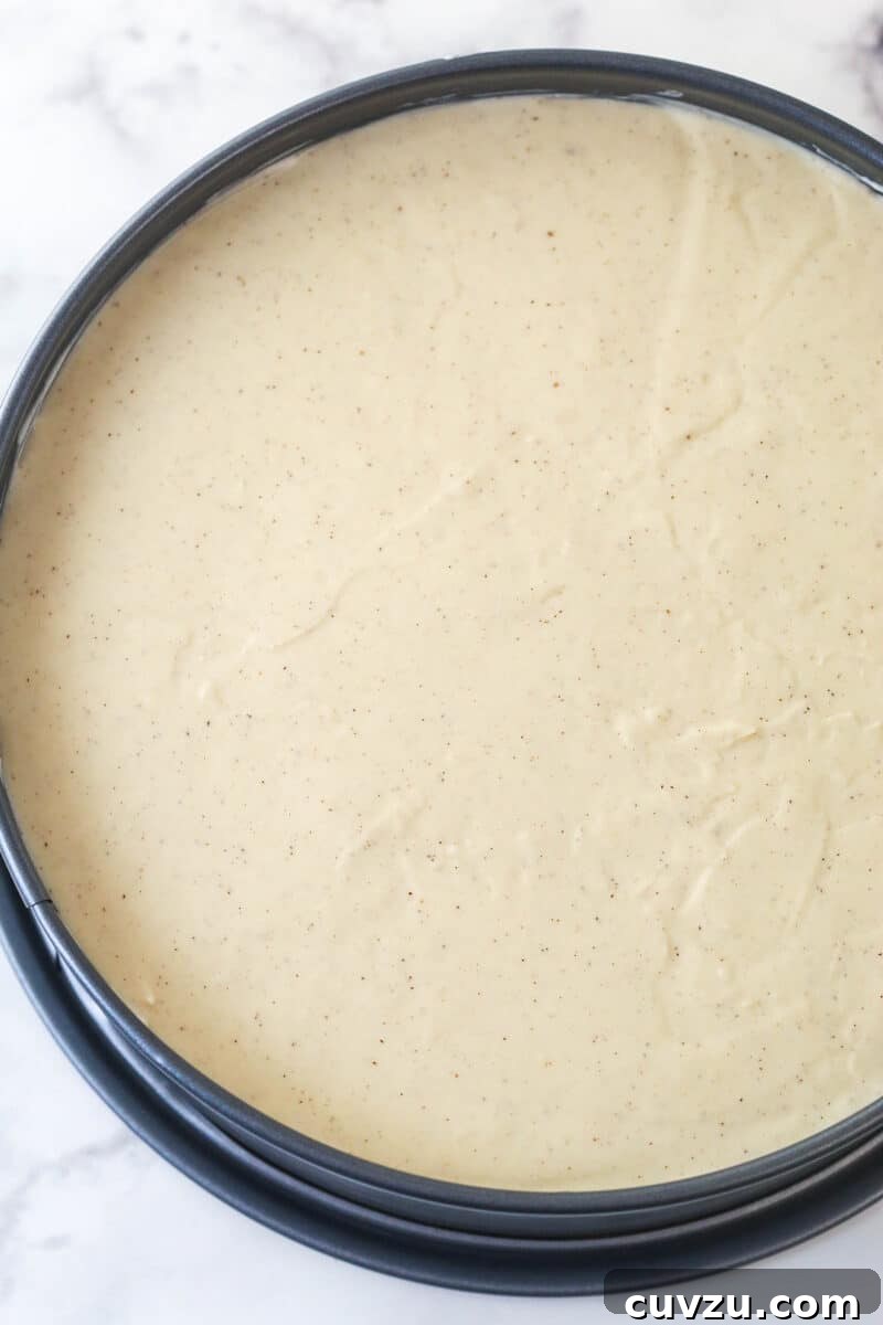 Decadent Caramel Apple Blondie Cheesecake 11 A springform pan filled with the smooth caramel apple cheesecake filling, spread evenly over the blondie base, ready for chilling.