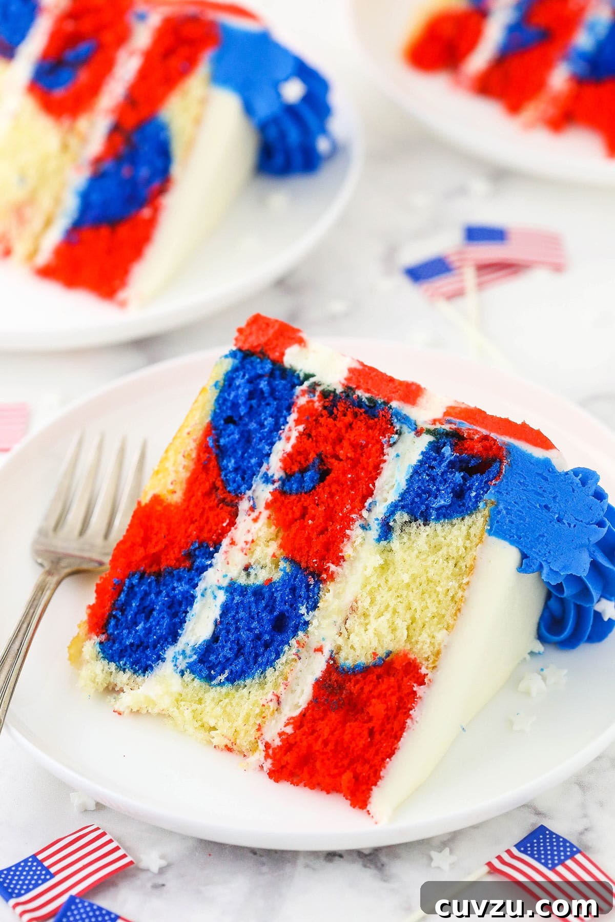 Fourth of July Swirl Cake 2 A piece of July 4th cake on a plate with two more slices behind it