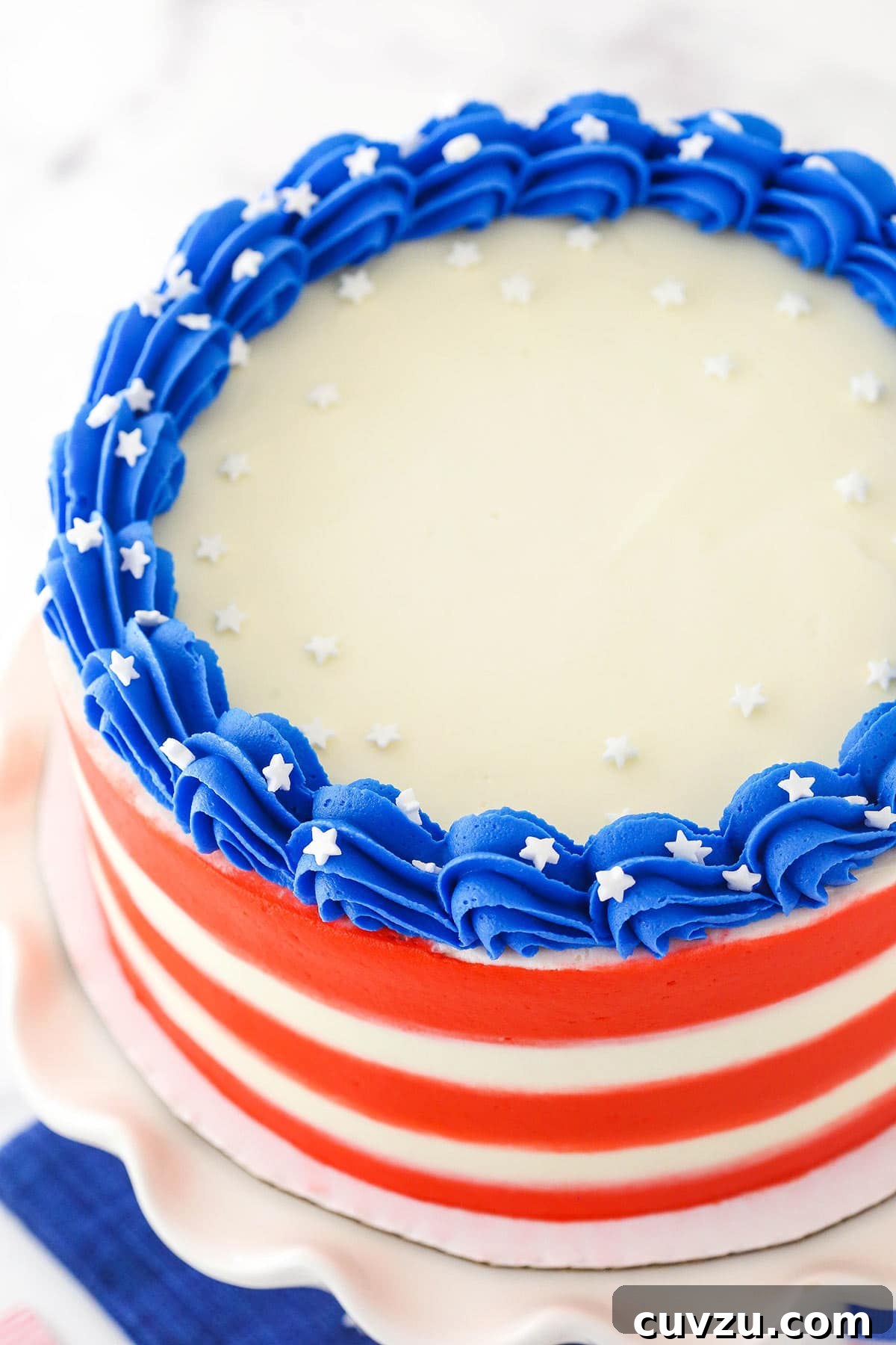 Fourth of July Swirl Cake 5 A July 4th marble cake on a white cake stand with white sprinkles garnishing the cake