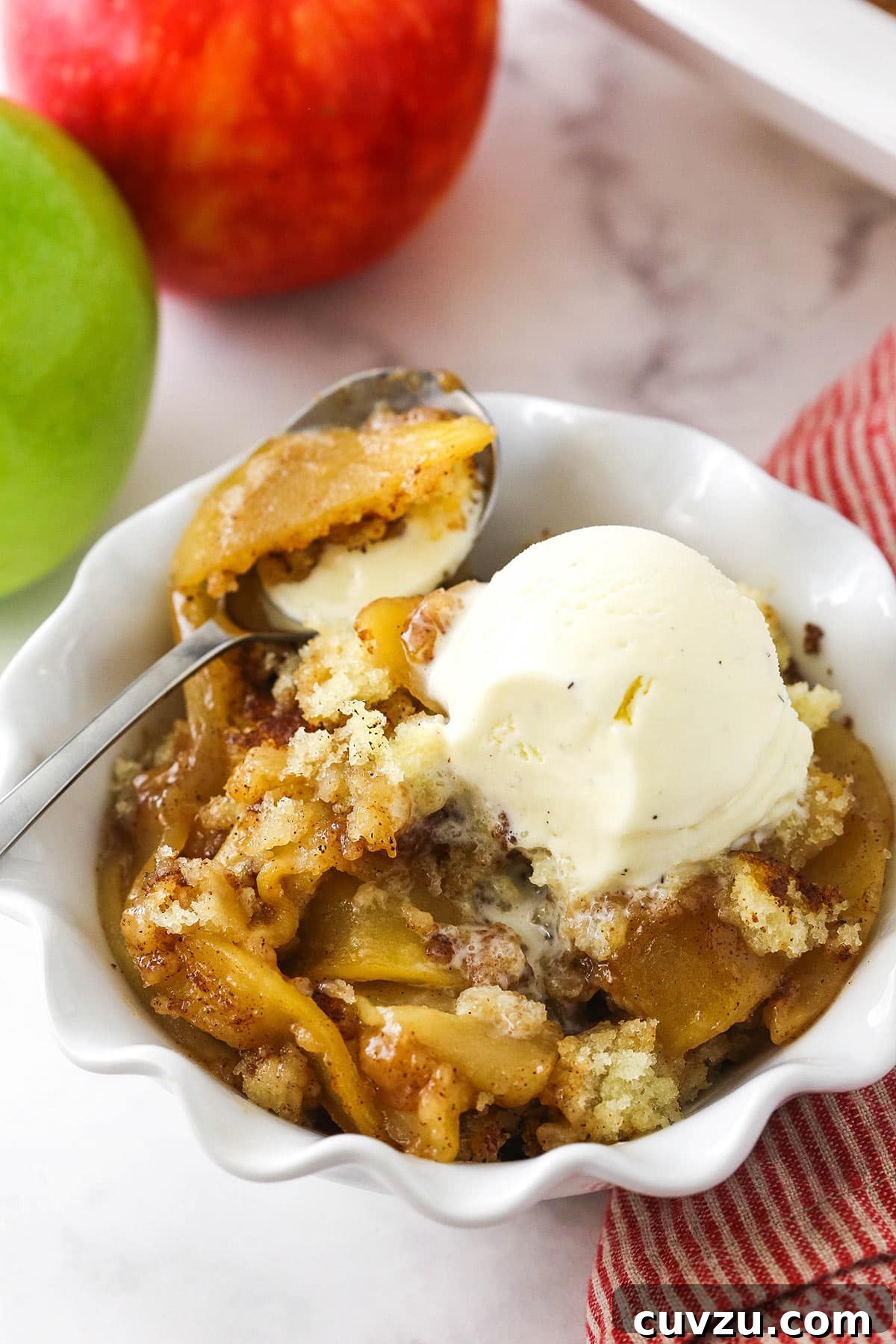 Filled with a sweet, melt-in-your-mouth cinnamon apple filling, this light and fluffy apple cobbler is truly the stuff dreams are made of! A bowl of apple cobbler topped with a scoop of vanilla bean ice cream.