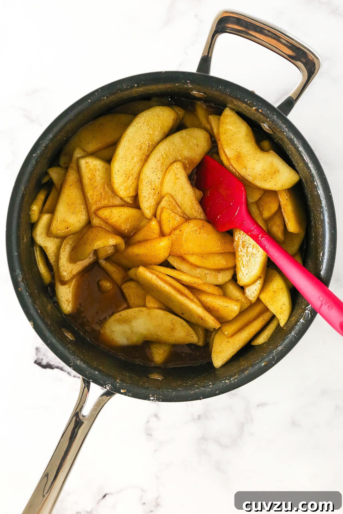 Filled with a sweet, melt-in-your-mouth cinnamon apple filling, this light and fluffy apple cobbler is truly the stuff dreams are made of! The pre-cooked filling in a pot being stirred by a rubber spatula.