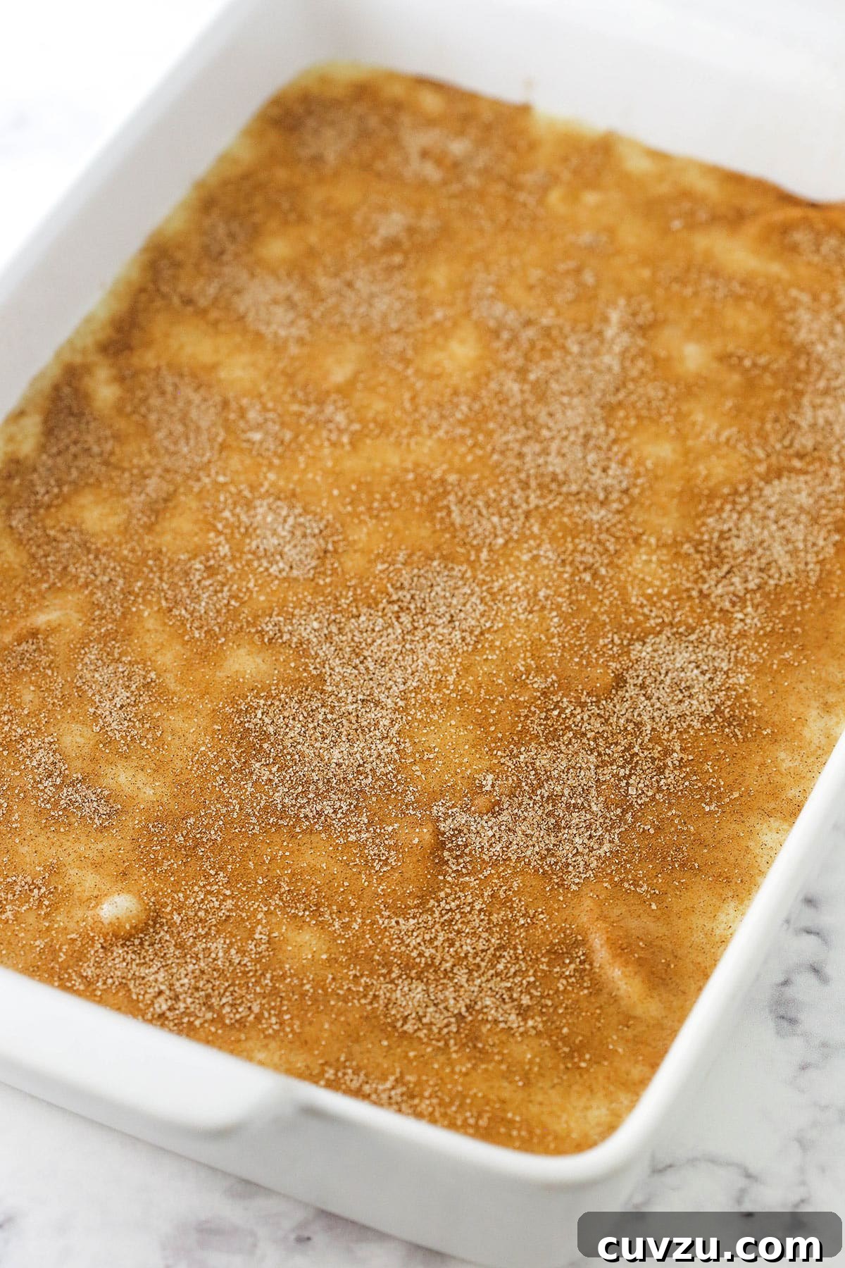 Filled with a sweet, melt-in-your-mouth cinnamon apple filling, this light and fluffy apple cobbler is truly the stuff dreams are made of! An unbaked apple cobbler inside of a white baking dish with handles.