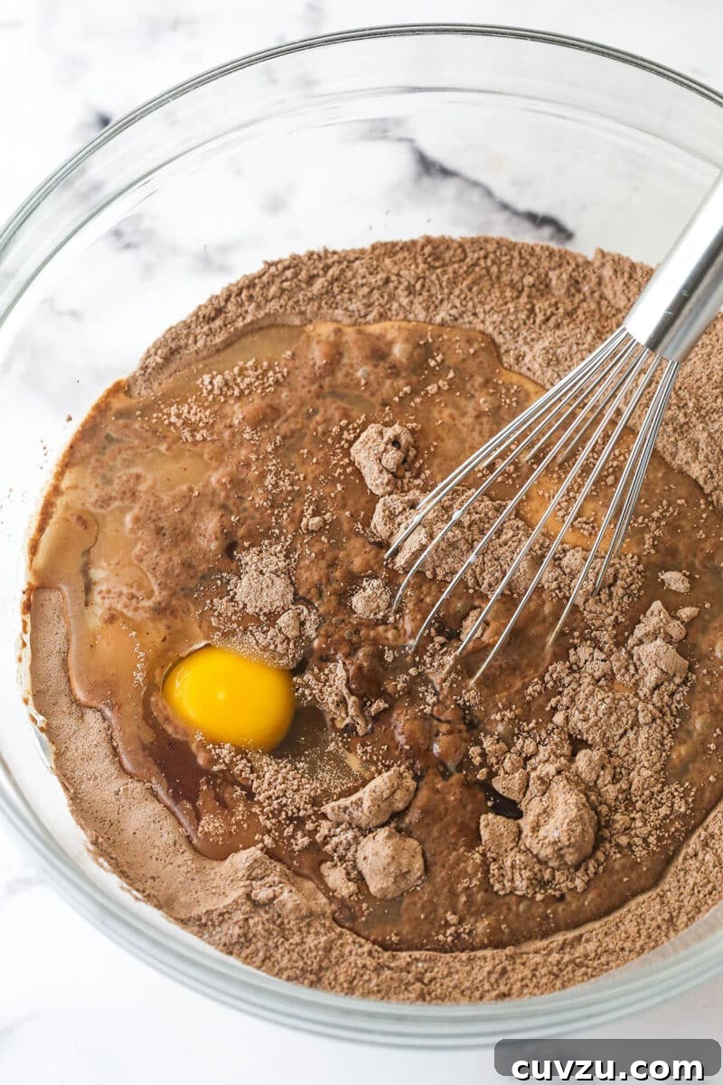These Black Bottom Cupcakes combine two desserts in one with a rich chocolate cupcake and a creamy chocolate chip cheesecake filling. Whisking egg into dry cupcake ingredients