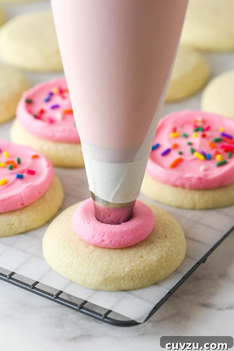 Pipe frosting onto cookies Piping pink buttercream onto a cookie
