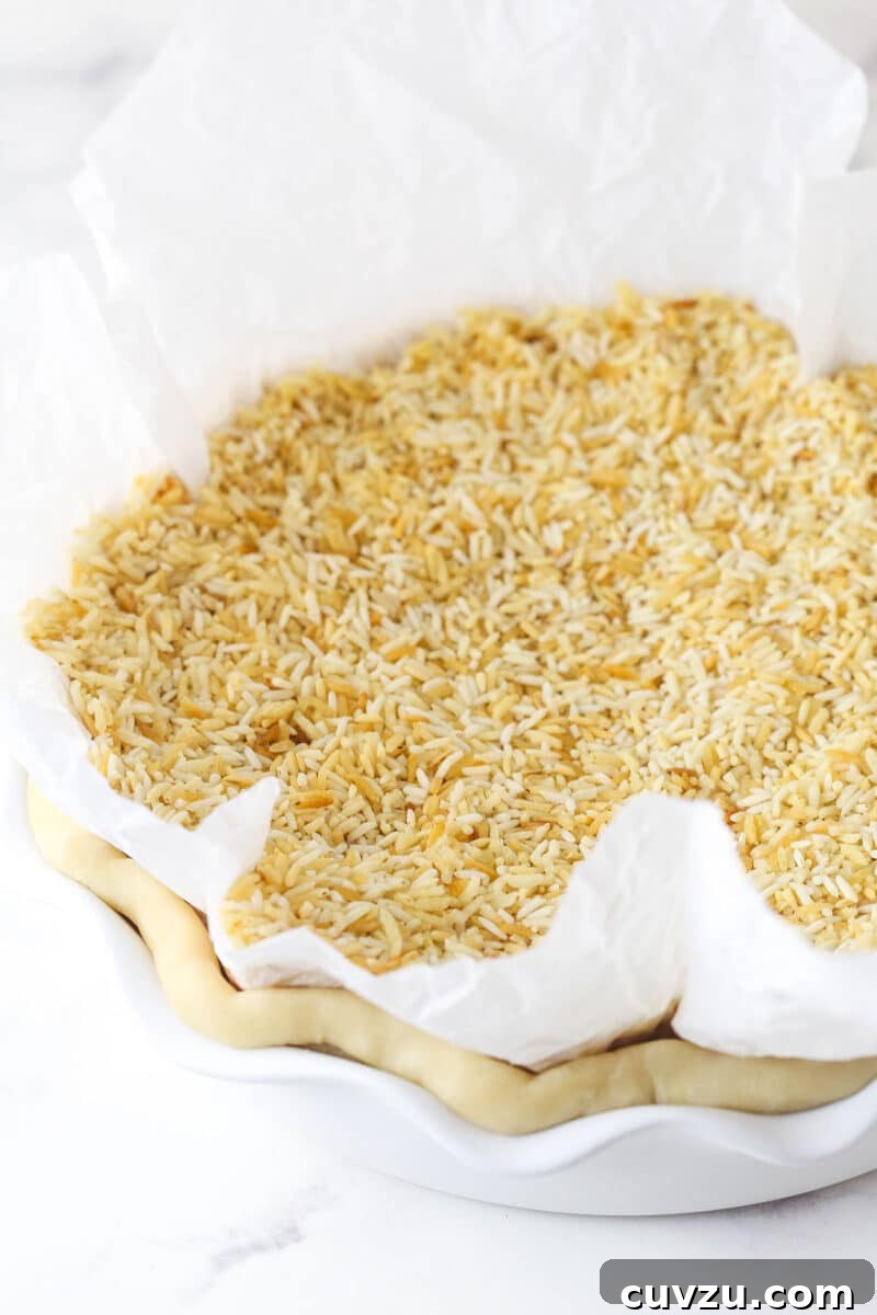 Classic Lemon Meringue Pie Recipe with Flaky Crust and Zesty Filling 3 Parchment paper and rice on a pie crust to blind bake it