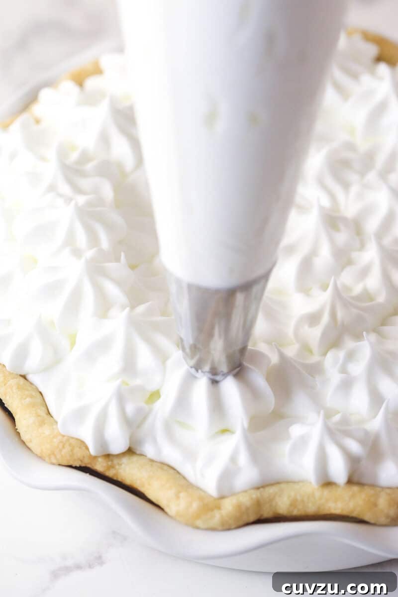 This classic lemon meringue pie features a tart lemon filling in a buttery crust topped with a light but stable meringue. Piping meringue onto a pie