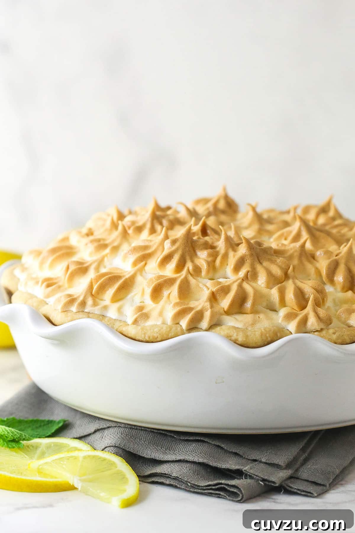 This classic lemon meringue pie features a tart lemon filling in a buttery crust topped with a light but stable meringue. Side view of a lemon meringue pie