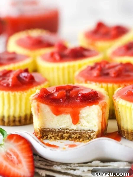 A mini strawberry cheesecake with a bite taken out of it.